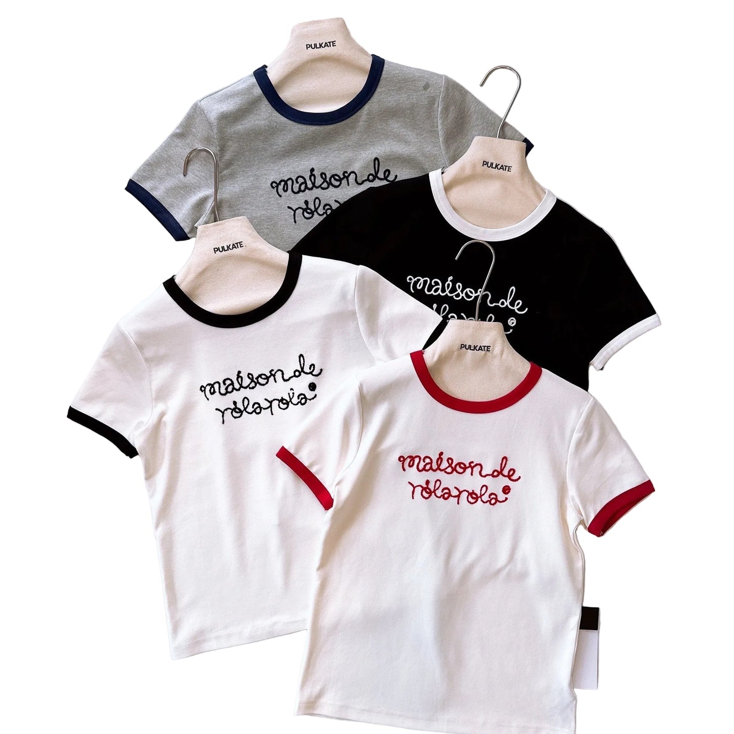 Four t-shirts with different color combinations and text on hangers against a white background.